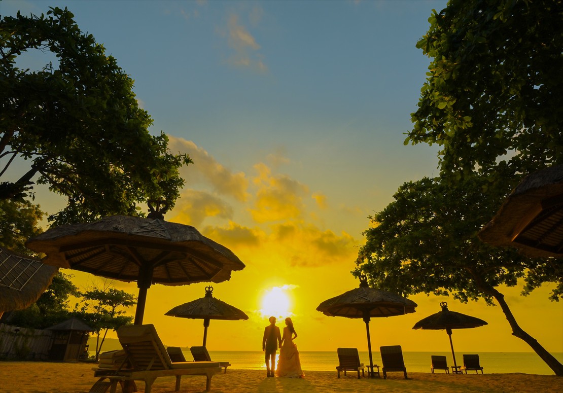 水平線に沈む夕日を一望する人影の薄いビーチ